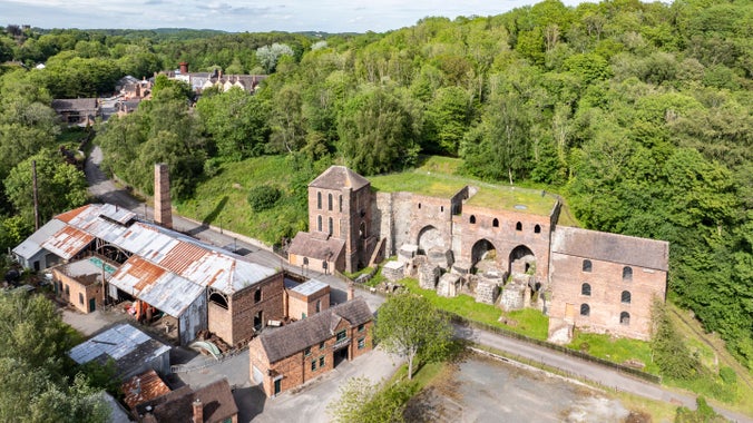 Image taken from a drone high over Blists Hill, Ironbridge, Shropshire. Brick buildings with rusting iron roofs are in the lower left hand corner of the image. Long disused Victorian brick built furnaces are in the top right.
